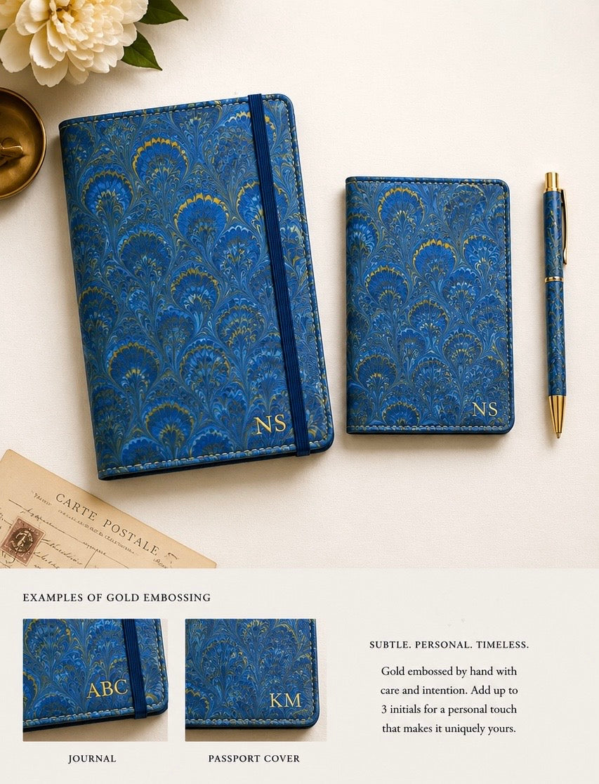 Blue patterned travel journal, matching passport cover, and coordinating pen displayed together, with examples of gold embossed initials on the journal and passport cover.