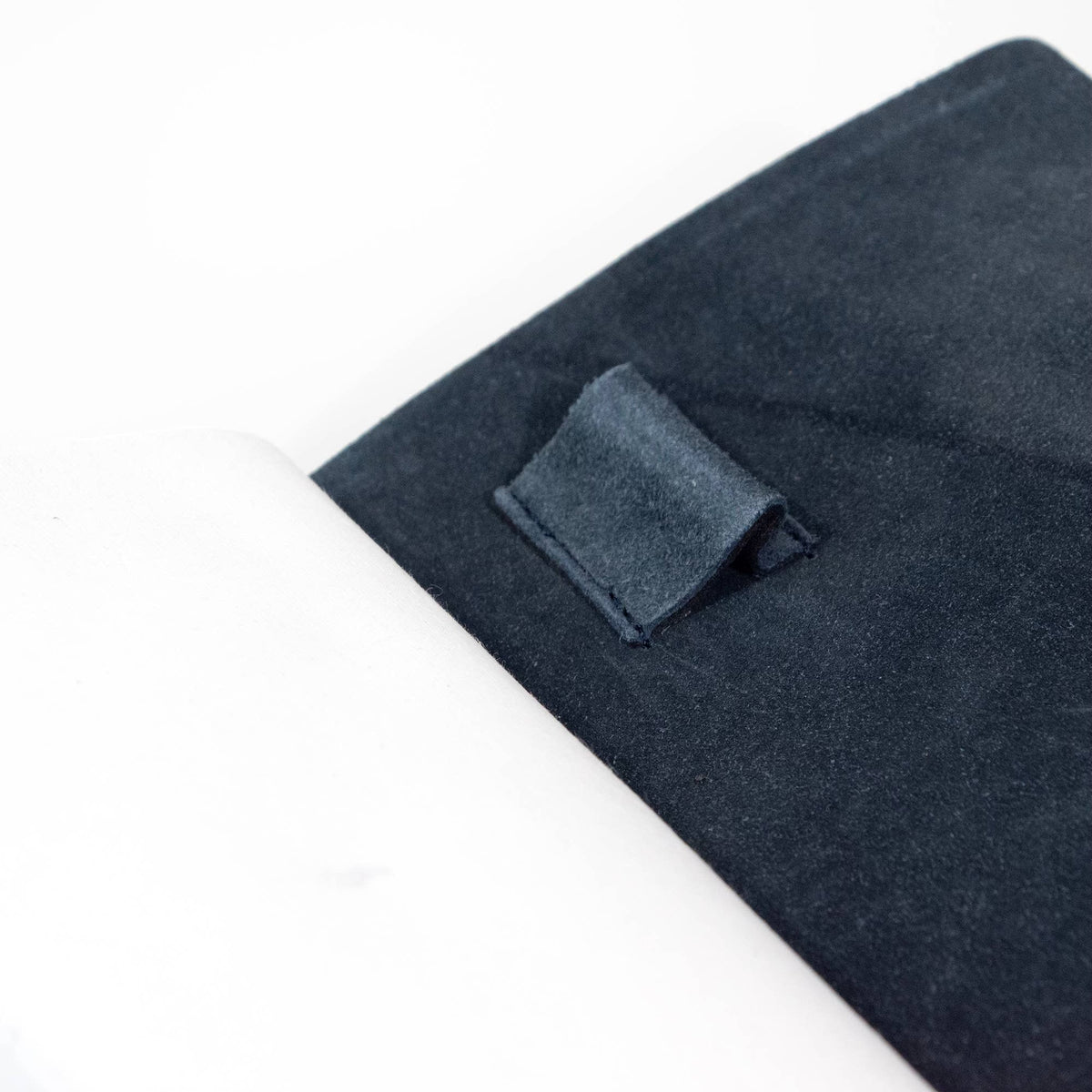 Close-up of the navy journal interior, showing the textured cover lining and built-in pen loop beside the white pages.