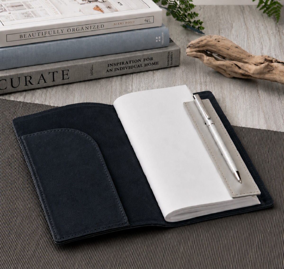 Open navy journal with a white writing pad and silver pen, showing the interior pocket and soft textured cover.