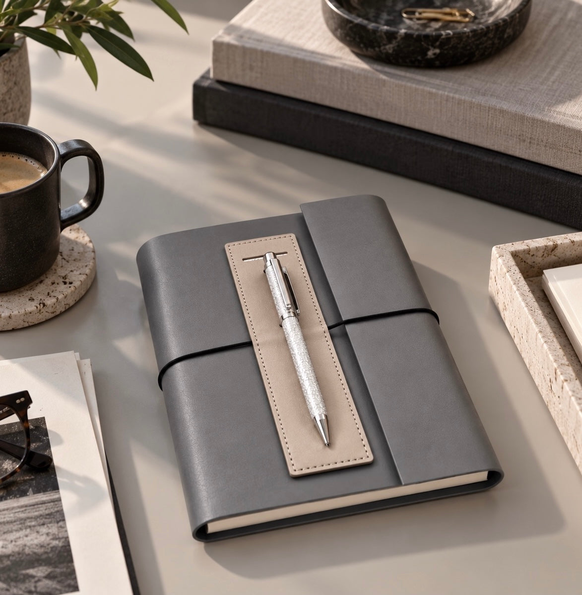 Light grey leather journal with silver pen on a desk