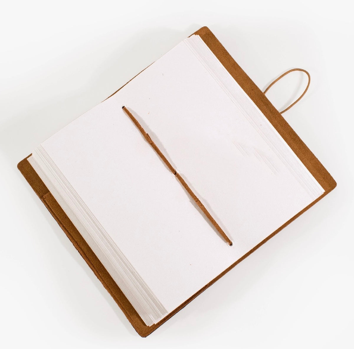 Open tan suede journal with blank pages and a matching tan elastic closure, photographed on a white background.