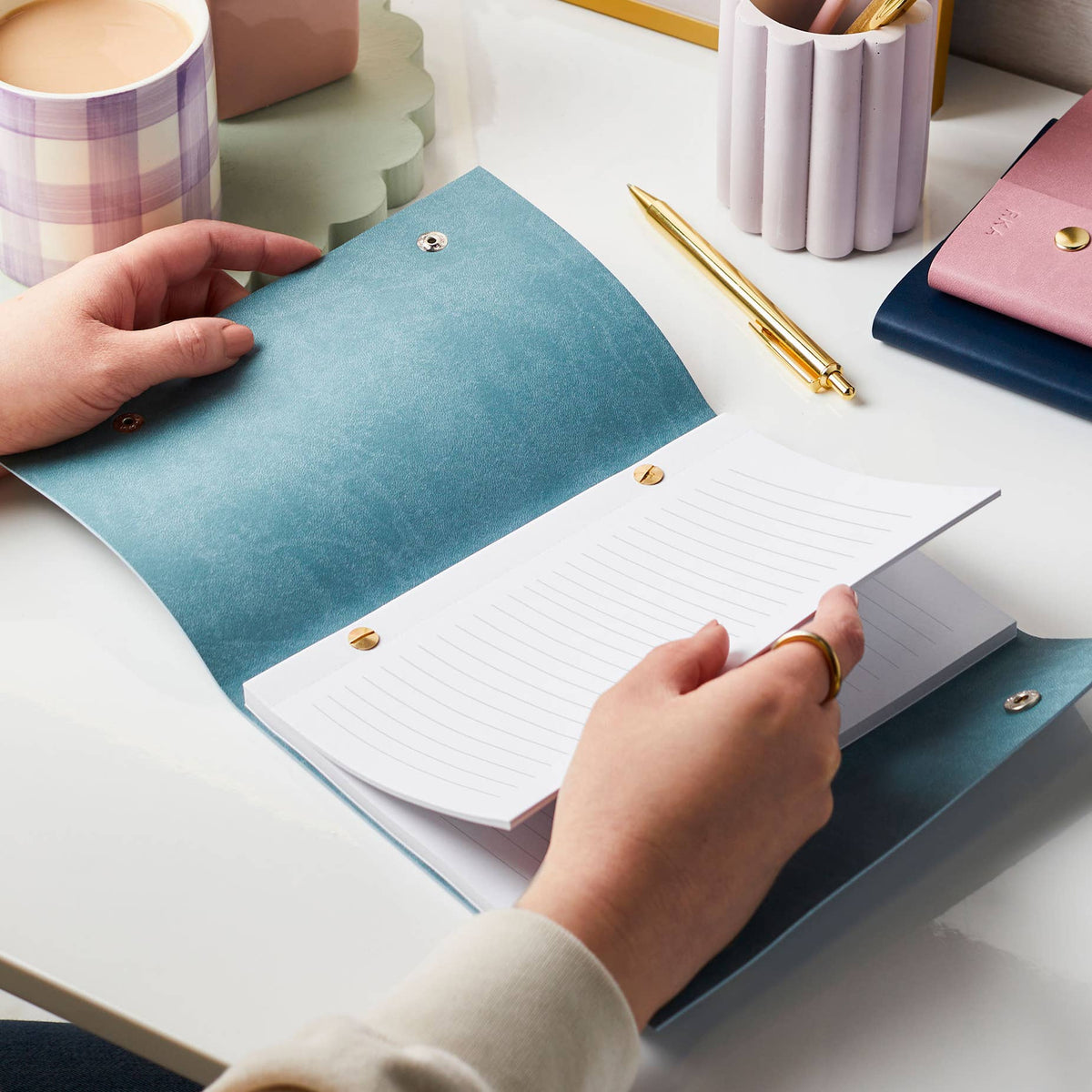 Teal leather journal open to lined pages with gold pen